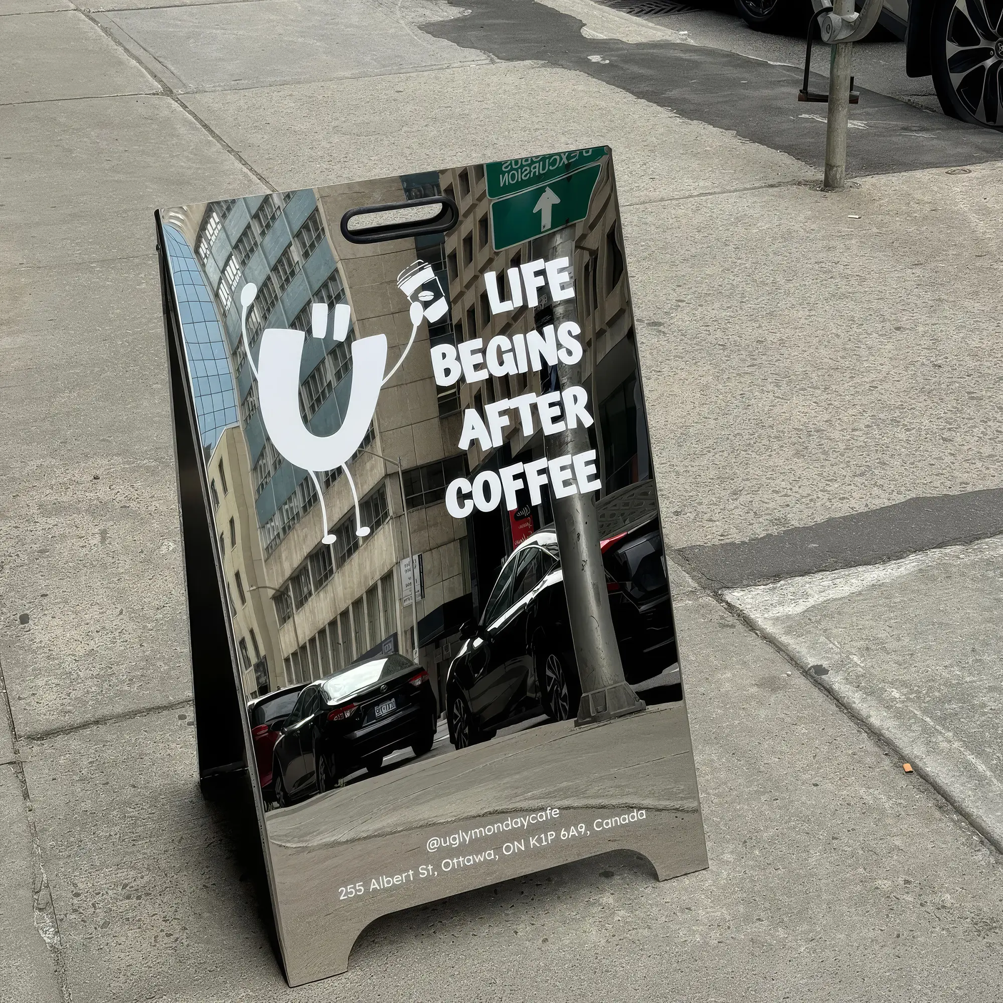 Mirrored chrome A-frame sidewalk sign for a coffee shop, featuring a playful logo and white text reading 'LIFE BEGINS AFTER COFFEE'.